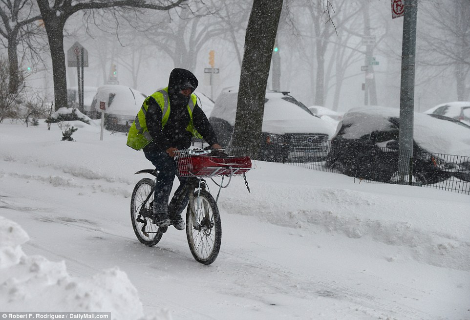 A delivery man on a bike navigates his way through Manhattan on Saturday as snow continues to fall an is due to continue overnight