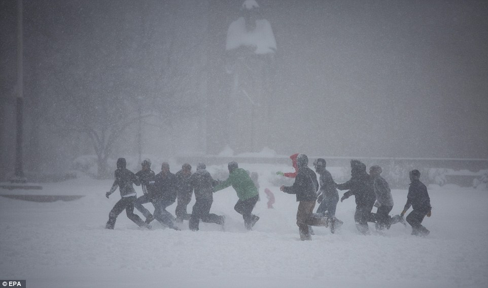 A group of bundled-up men play football in the snow in Downtown Brooklyn in New York on Saturday.