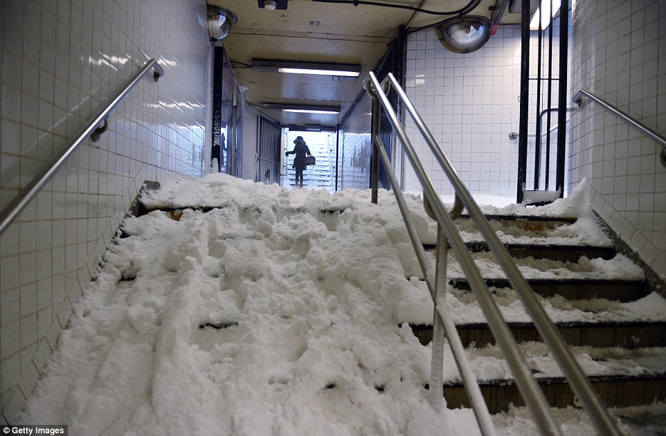 A woman carefully enters Columbia Circle subway stop, where the stairs were covered in packed snow, on Saturday