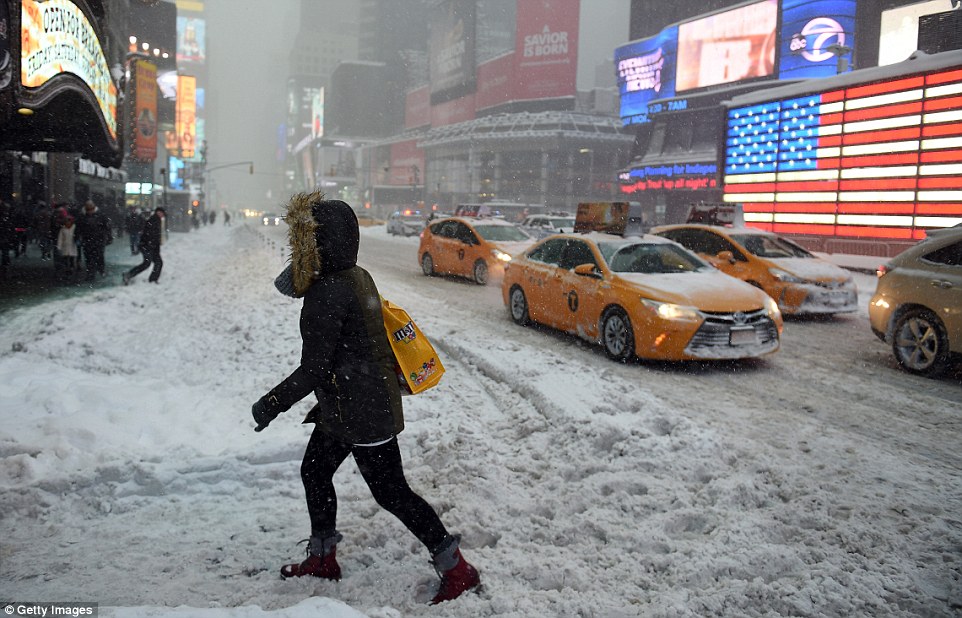 Pedestrians cope with snow covering sidewalks and streets in Time Square as the city filled with snow from storm Jonas tonight