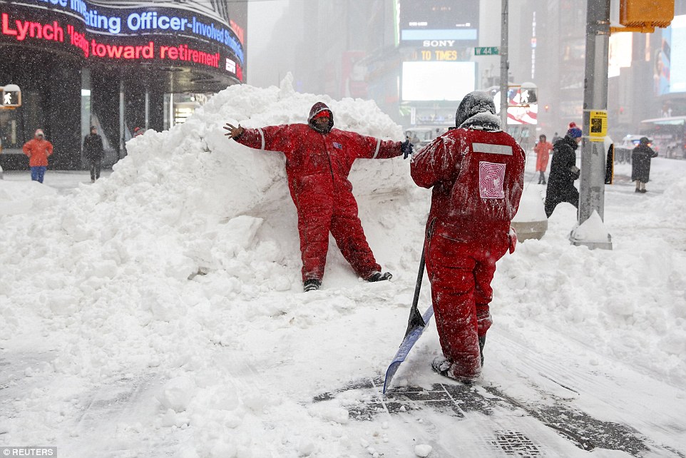 Workers take a break in order to take selfies in Times Square as snow fell at a rate of up to 3 inches per hour, covering New York