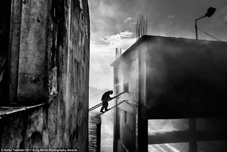 A firefighter crosses into a burning building to douse fire at Tampaco Foils Limited, a packaging factory in the Tongi industrial area near Dhaka, Bangladesh