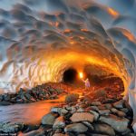 The walls and ceiling of the frozen world are made up of layers of compacted snow, with the river softly gurgling through a long chamber here illuminated by a yellow flare