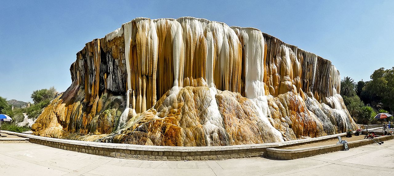 The dramatic, multicolored travertine walls of the spring have attracted thousands of visitors since the era of the Roman Empire and side e view of the hot springs