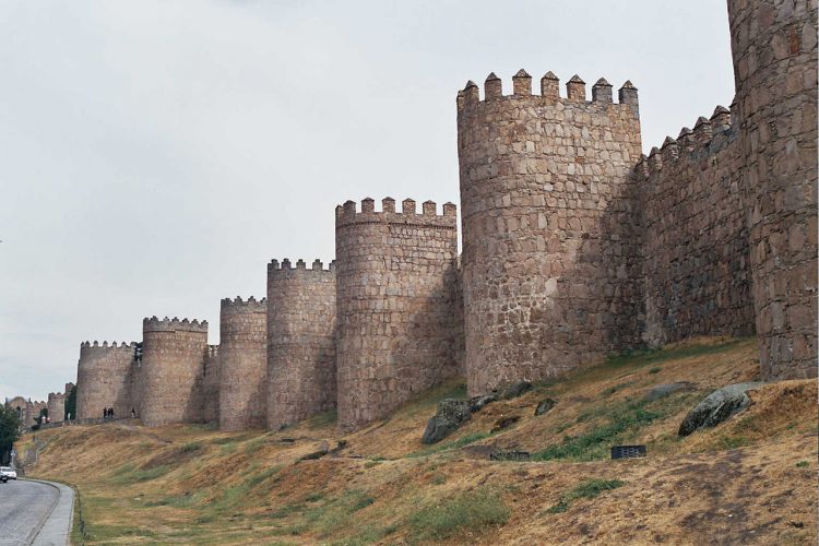 The Walls of Avila is built on the flat summit of a rocky outcrop which rises abruptly in the middle of a vast treeless plain strewn with immense grey boulders and surrounded by lofty mountains.