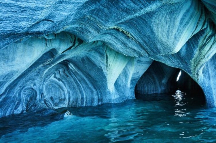 The early morning sunlight breaks into the openings of the Marble Caves reflects off the water and splashes the marble walls of the cave with distinct shades and patterns of blue hue.