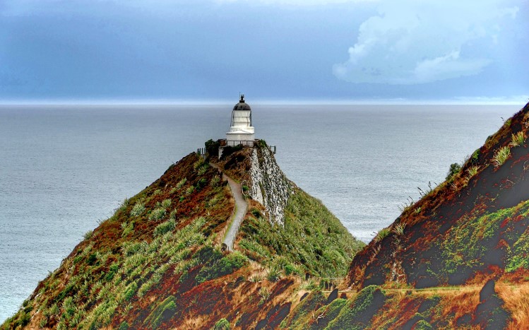 The historic lighthouse perches above the famous rocks that Captain Cook named Nugget Point because they resemble gold pieces.