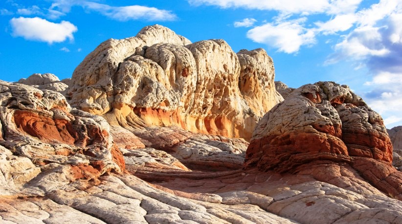 The White Pocket is a group of domes and ridges covering one square mile, with swirling, thin-layered strata, adjacent layers of contrasting color, and unique erosive features.