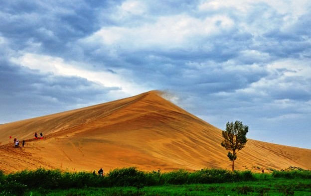 Drifting sands from steep sand dunes look like beautiful brocades on sand dunes, dancing golden dragons, or beautiful brocades hung up with beautiful singing sounds.